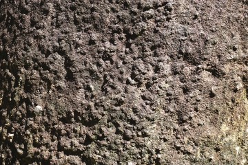 Closeup of rough stone background texture shaded from left to right