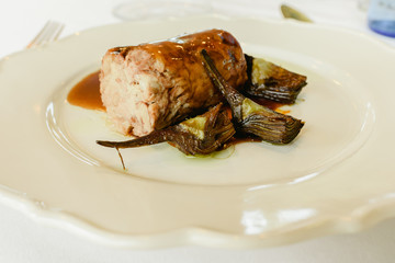 Plate of carefully prepared food, pork tenderloin confit with artichokes.