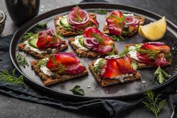 healthy sandwiches with wholegrain rye crisp bread, cream cheese, beet cured salmon and cucumber