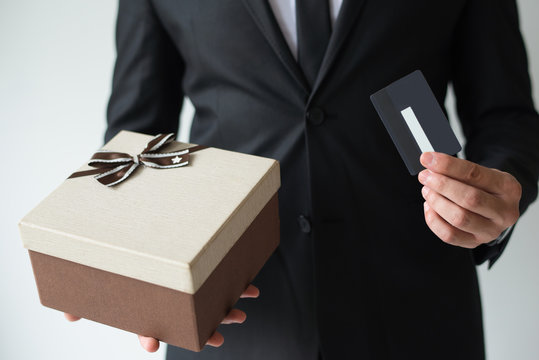 Close-up Of Businessman In Suit Buying Gift Card For Christmas Shopping. Unrecognizable Man Using Discount Card. Shopping Concept