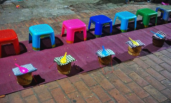 Colorful plastic stools and sticky rice baskets lined up pre-dawn for the morning alms-giving ritual in Luang Prabang, Laos