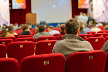 People in the auditorium on a business conferece. person back seating and watching f