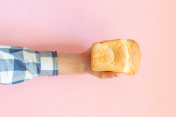 top view of person's hand holding a loaf bread  over the color background f