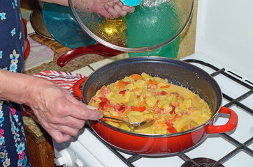 The hostess puts out the vegetables on a gas stove.