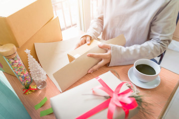 Wrap Christmas present. Close-up top view of man opening gift box on the wooden desk with Christmas...