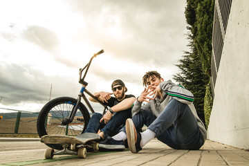 Young people riding bikes and skateboards in the city. Modern people with a skate and a bmx down...