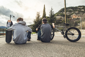 Young people riding bikes and skateboards in the city. Modern people with a skate and a bmx down the street © Rafa