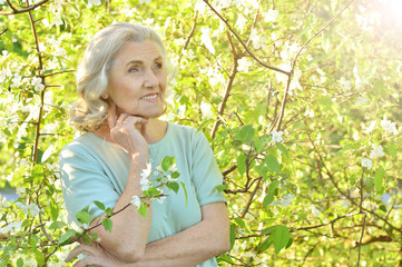 Beautiful senior woman posing near blooming tree