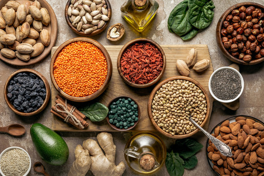 flat lay of legumes, superfoods and healthy ingredients on wooden board with rustic background