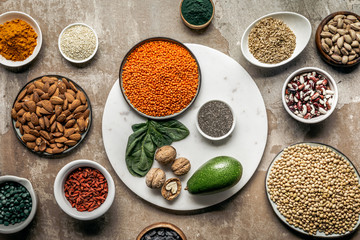 flat lay of superfoods, legumes, nuts and avocado on textured rustic background