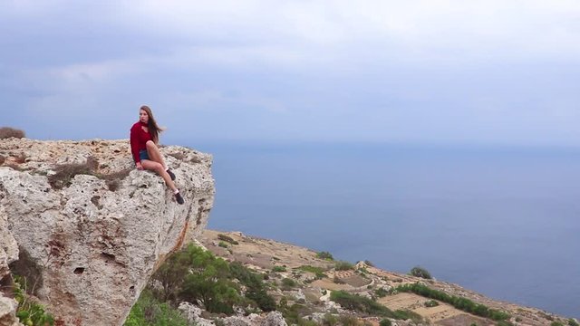 Girl sitting on the stone on Dingli Cliffs - the famous natural landmark in Northern Region of Malta