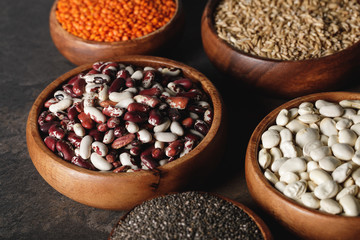 Fototapeta premium variety of beans, lentils and oat groats in wooden bowls on table