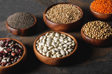 Fototapeta premium variety of beans, chia seeds and oat groats in wooden bowls on table