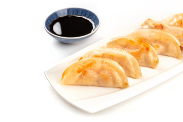 Gyozas, Asian dumplings, on a white background with a bowl of soy sauce and a place for text