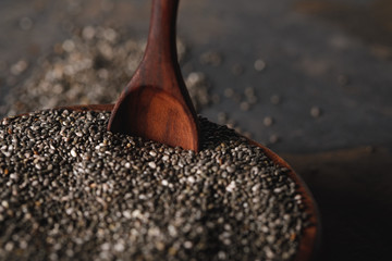 selective focus of chia seeds in wooden bowl with spoon