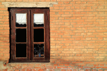 Dark brown wooden window on terracotta brick wall in sunlight 