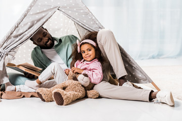 african american father reading book with child and smiling in wigwam © LIGHTFIELD STUDIOS