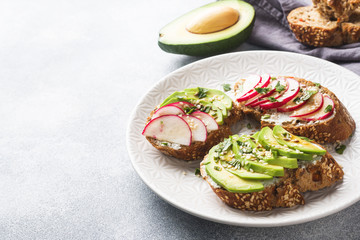 Cereal bread sandwiches with cottage cheese, fresh avocado and radish.