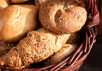 Mix fresh bread in basket on wooden background in still life. Top view. Concept of food, space for your text.