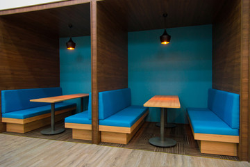 Cozy blue sofas near table in popular cafe. Modern interior of public establishment with compartment walls. Coworking space concept