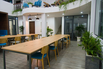 Long tables and chairs in modern meeting room with green plants. Coworking space with balcony. Conference room concept