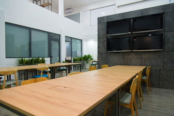 Modern conference hall with plasma displays and long tables. Green plants near wall.  Creative...