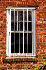 White painted window with security grill on old brick facade