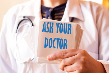 Doctor holding sticky with ASK YOUR DOCTOR 
