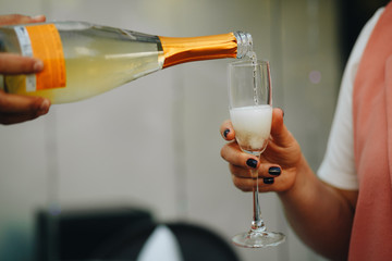 Hand of the waiter pours white wine or champagne in wineglass. Bright picture of pouring wine into glasses.