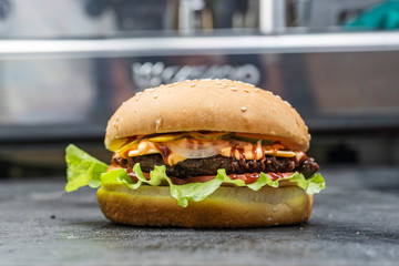 Classic burgers with becon, meat, cheese, onion, tomato and cheese and integral bun. On textured black board. Flat lay.