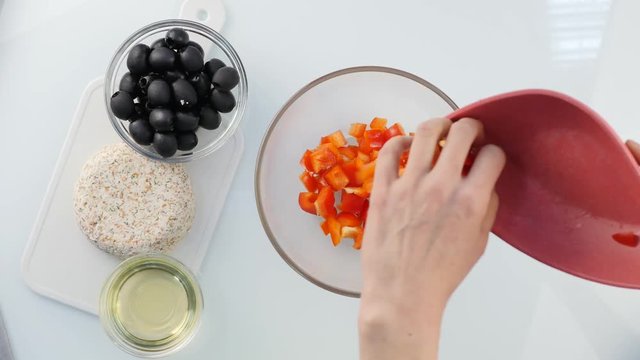 Top view. woman cooking vegetarian low calorie Greek salad, puts vegetables in a bowl. 4K