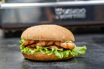 Classic burgers with becon, meat, cheese, onion, tomato and cheese and integral bun. On textured black board. Flat lay.