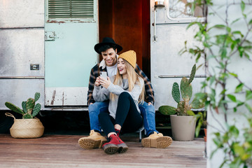 Young couple using smartphone near van