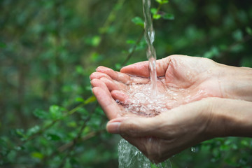 closeup water flowing to hand of women for nature concept in the garden background.