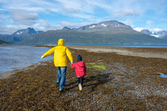Norway, mother and daughter running at the beach, Lyngen fjord