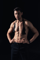 handsome shirtless man standing akimbo and looking at camera isolated on black
