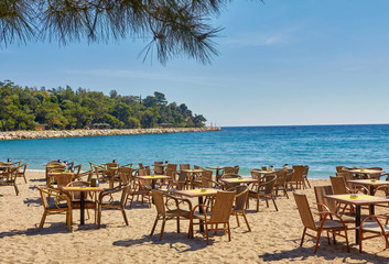 Tables and chairs on terrace in outdoor restaurant with view in Kemer, Turkey.