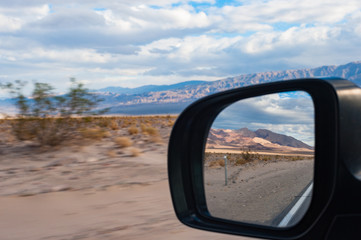 Diving through death valley highway, view through car mirror, landscape zooming by motion blur