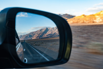 Diving through death valley highway at sunset, view through car mirror, landscape zooming by motion blur