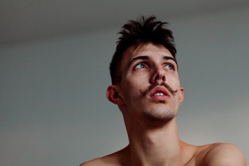 Naklejka premium Young shirtless man with mustache thinking