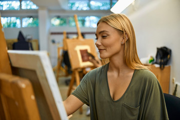 Smiling student painting on easel in art class