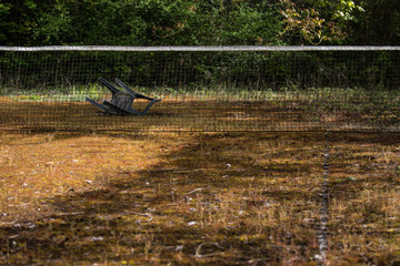 banc renversé sur un terrain de tennis abandonné