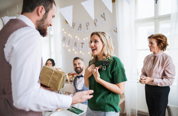 Obraz premium A man giving gift to a young surprised woman on a family birthday party.