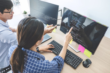 Two professional programmers cooperating at Developing programming and website working in a software develop company office, writing codes and typing data code