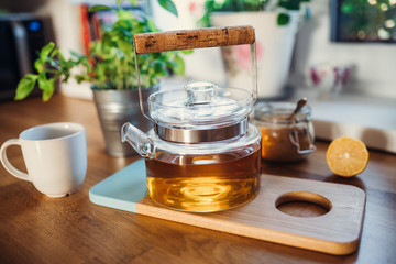 Composition of tea in a teapot, sugar, lemon and cup on wooden table.