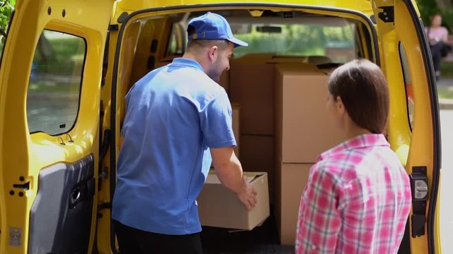 Diligent deliverer take out box from yellow car to give it to woman