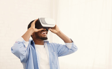 Joyful black man using VR headset at home