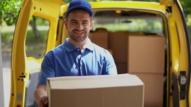 Smiling happy courier man in front of open van doors delivers package