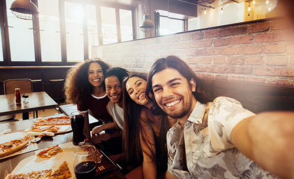 Group of multi-ethnic friends making selfie at restaurant