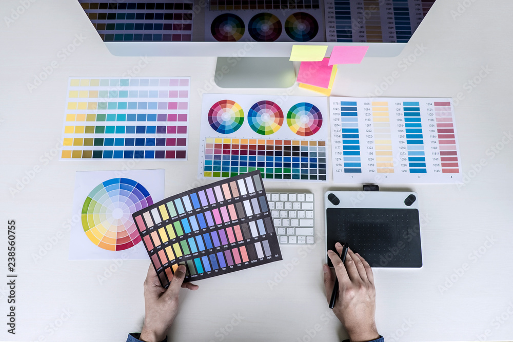 Poster male creative graphic designer working on color selection and color swatches, drawing on graphics ta
